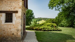 A stone building with a window and a door, surrounded by a well-maintained garden and trees. - Authentic gîte on estate with swimming pool (Issac)