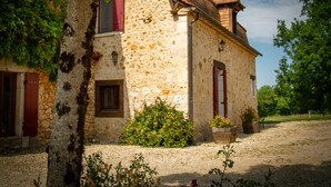 A rustic stone building with a sloped roof, a wooden door, and a window with shutters. - Authentic gîte on estate with swimming pool (Issac)