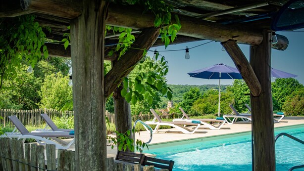 A pool area with wooden pergolas, lounge chairs, and a clear view of the pool. - Authentic gîte on estate with swimming pool (Issac)