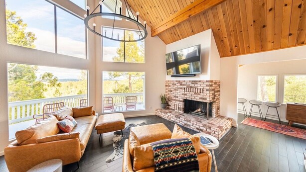 Un amplio salón con chimenea, ventanas grandes y un techo alto con vigas de madera.