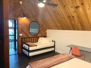 Une chambre confortable avec un plafond en bois, un lit, un bureau et une chaise.