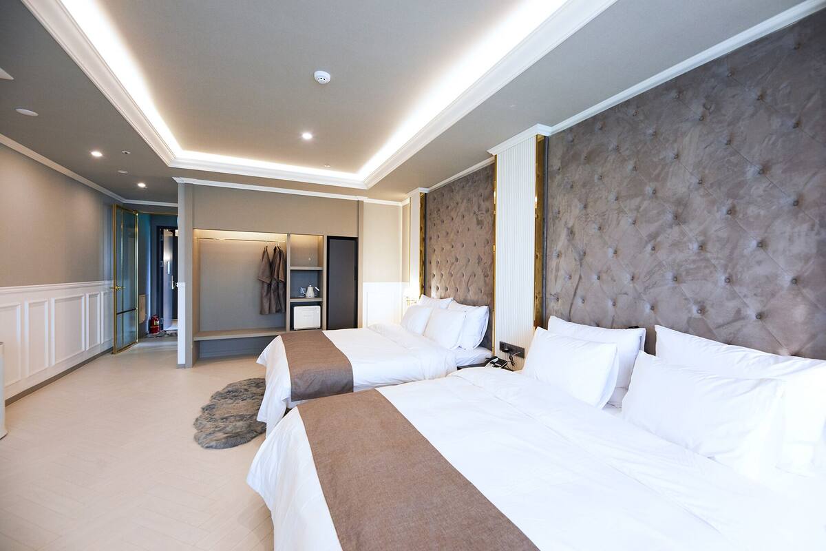 Una habitación de hotel con dos camas, un cabecero grande con capitonado y un vestidor.