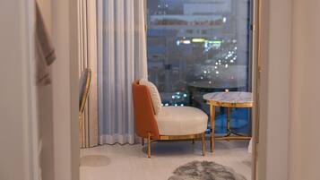 A modern living room with a white sofa, a round marble table, and a view of a cityscape at night.