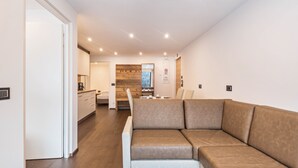 Et moderne interiør med sofa, trægulv, et køkken og et spisebord.