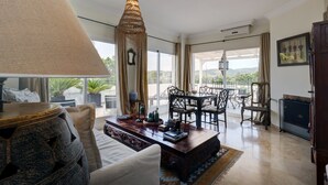 A spacious living area with a large window, a dining table, and a decorative lamp. - Apartamento "Del Paraíso" with Mountain View, Shared Pool and Private Terrace (Estepona)