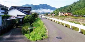 Une route de campagne bordée d’une clôture blanche, d’un panneau indicateur et de maisons de chaque côté.