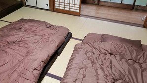 Two beds with brown bedding in a room with tatami flooring and a sliding door in the background. - Tuwano sou (Tsuwano)