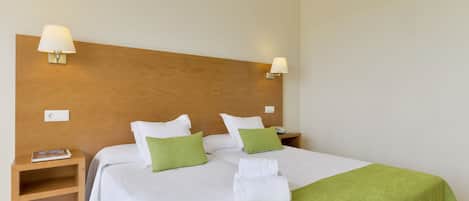 Una cama bien hecha con ropa de cama blanca y verde, dos mesitas de noche con lámparas y un cabecero de madera.