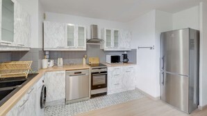A modern kitchen with white marble cabinets, stainless steel appliances, and a wooden countertop. - Chic and spacious apart with parking (Saint-Germain-en-Laye)