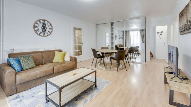 A modern living room with a brown sofa, a wooden coffee table, and a dining area with a table and chairs. - Chic and spacious apart with parking (Saint-Germain-en-Laye)