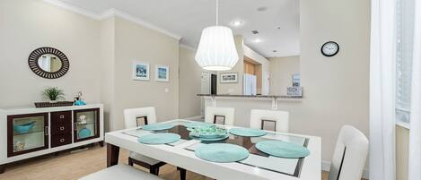 Un comedor con una mesa blanca, individuales color turquesa y sillas blancas.