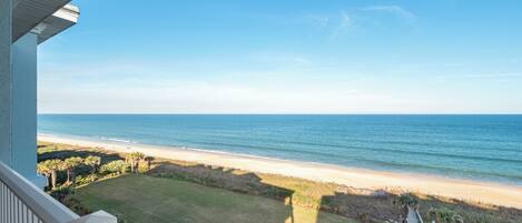 A balcony with a view of a beach and ocean.