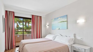 Een slaapkamer met een bed, nachtkastje, schilderij en een raam met gordijnen.