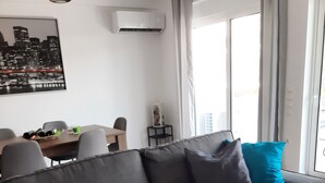 A modern living room with a grey sofa, a dining table with chairs, and a cityscape artwork on the wall. - Διαμέρισμα  (Αθηνα)