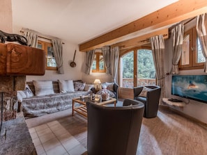 A cozy living room with a sofa, armchairs, a coffee table, and a TV.