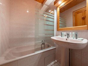 Un bagno con una vasca, un lavandino e uno specchio.
