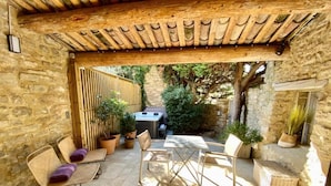 A stone-walled patio with a wooden pergola, outdoor furniture, and potted plants. - CHAMBRE GRAND CONFORT COQUET with PRIVATE JACUZZI (Martignargues)