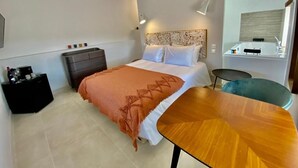Une chambre d’hôtel moderne équipée d’un lit, d’une table de chevet et d’un petit bureau avec une chaise.