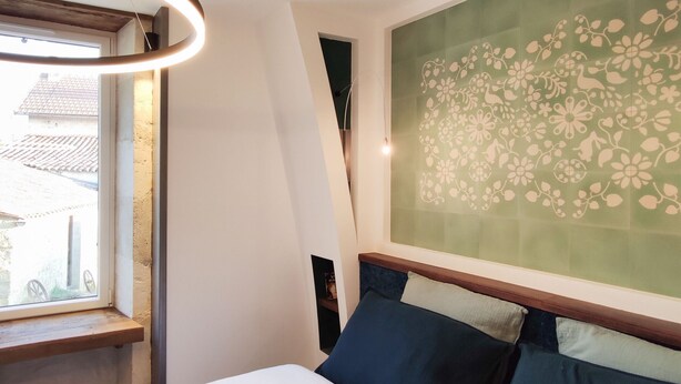 Un dormitorio con cama, ventana y pared con estampado floral.