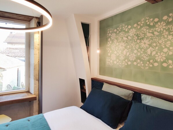 Un dormitorio con cama, ventana y pared con estampado floral.