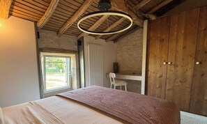 A bedroom with a bed, a window, a chair, and wooden walls.