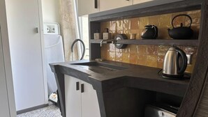 Una cocina moderna con cubierta negra, una tetera y una cafetera.