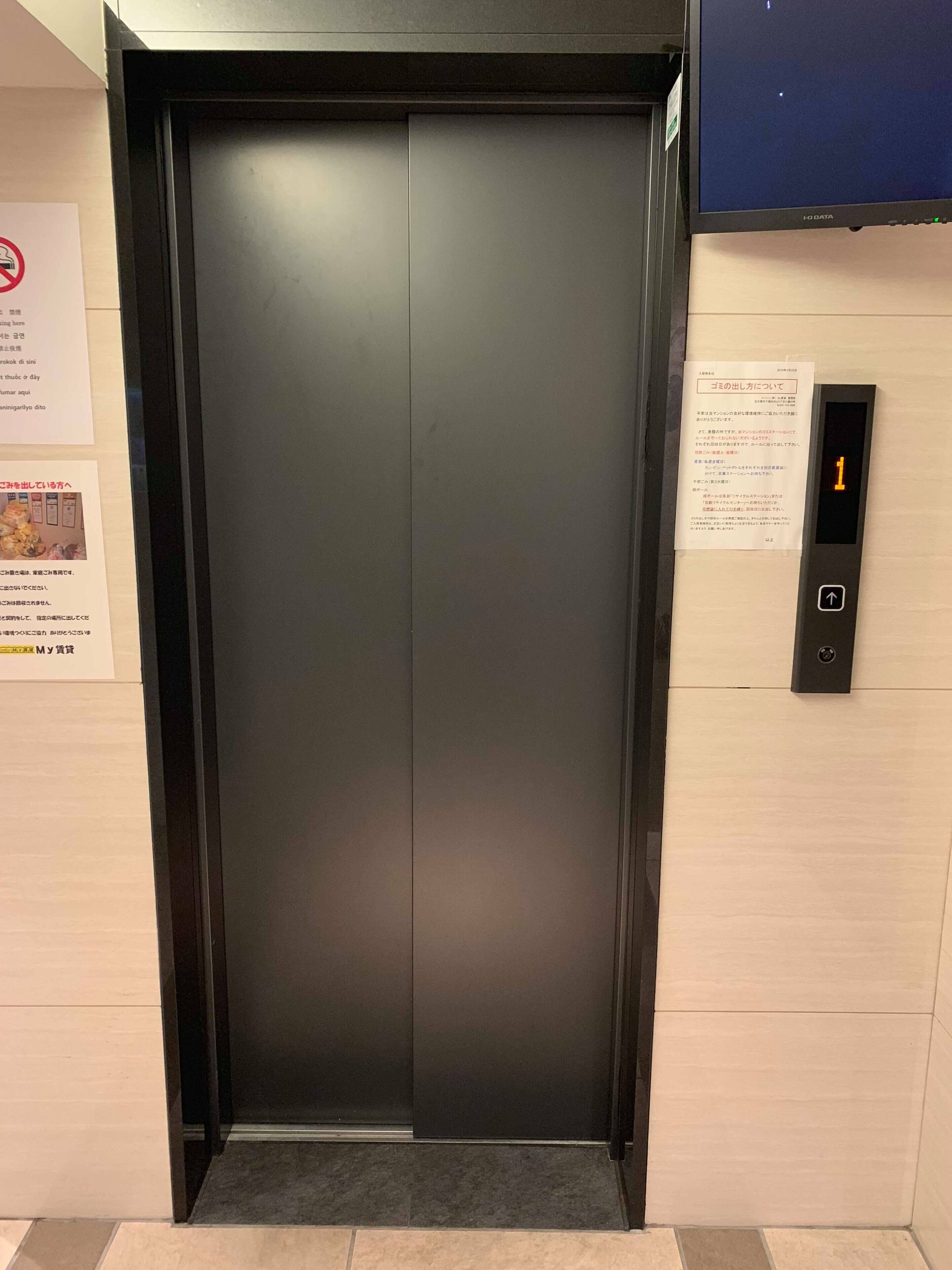 Un ascensor moderno con un panel de control digital en el lado derecho.
