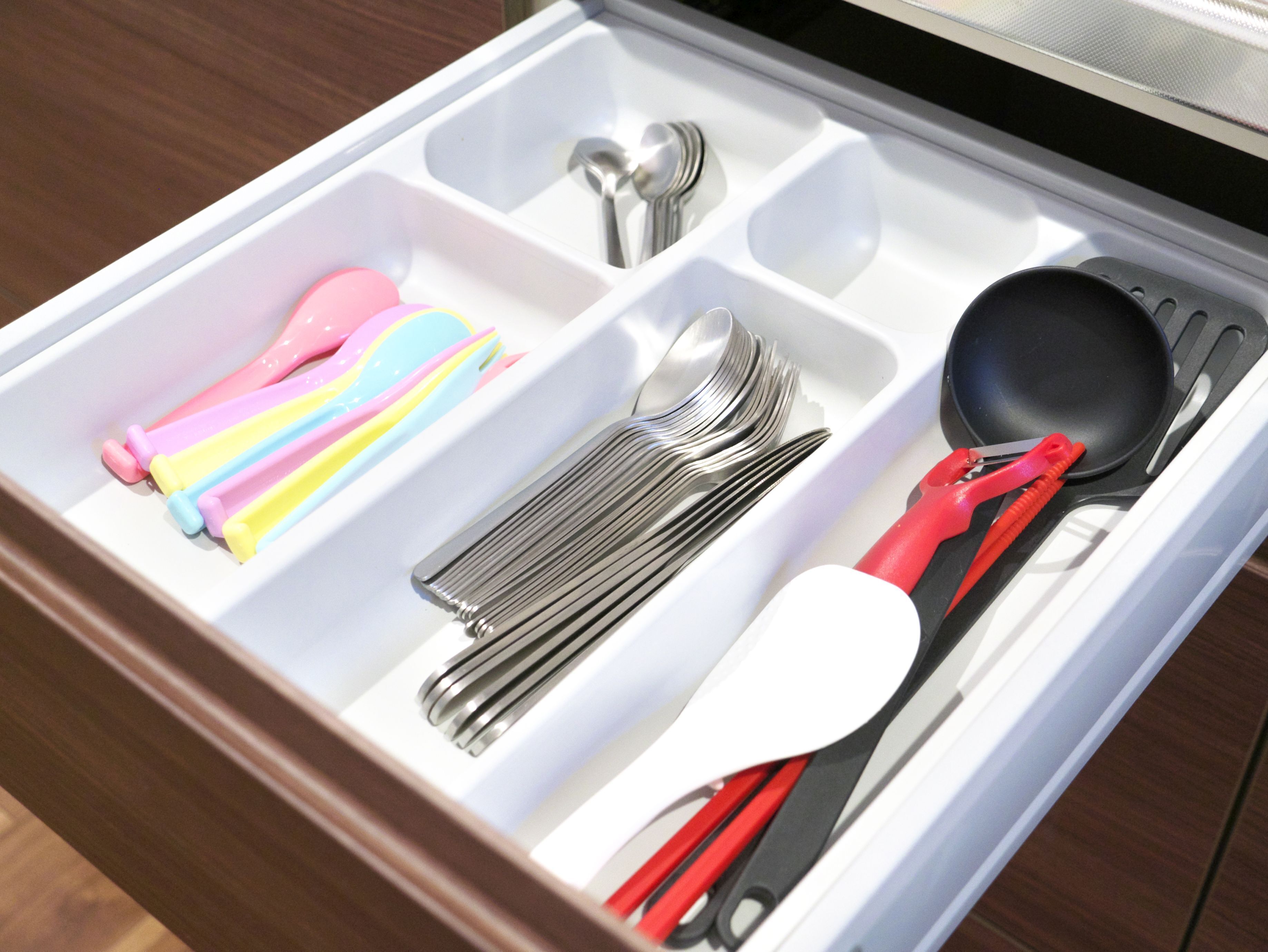 A drawer with compartments containing utensils, including forks, spoons, and a spatula.