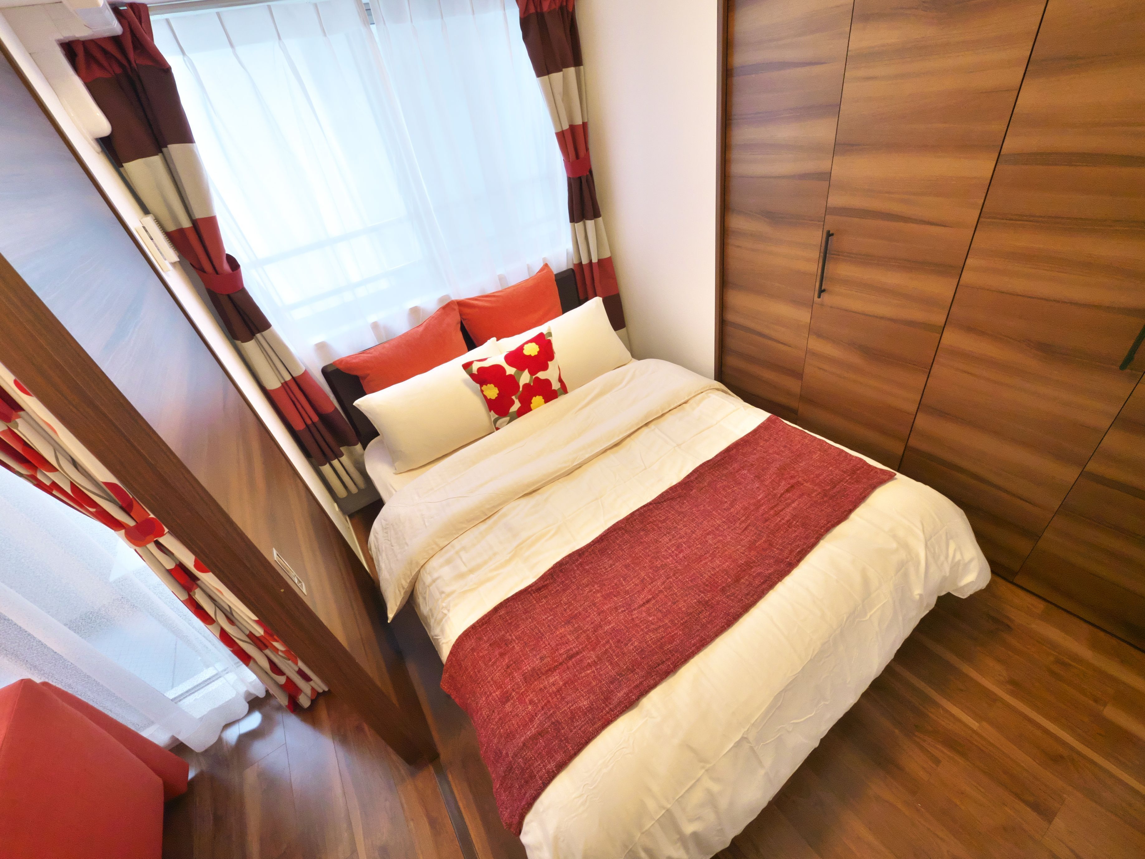 Un dormitorio con cama, cortinas y un armario de madera.