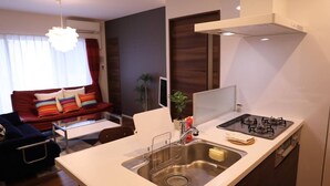 A modern kitchen with a gas stove, stainless steel sink, and a white countertop. - Kicon-hotels Marunouchi (Nagoya)
