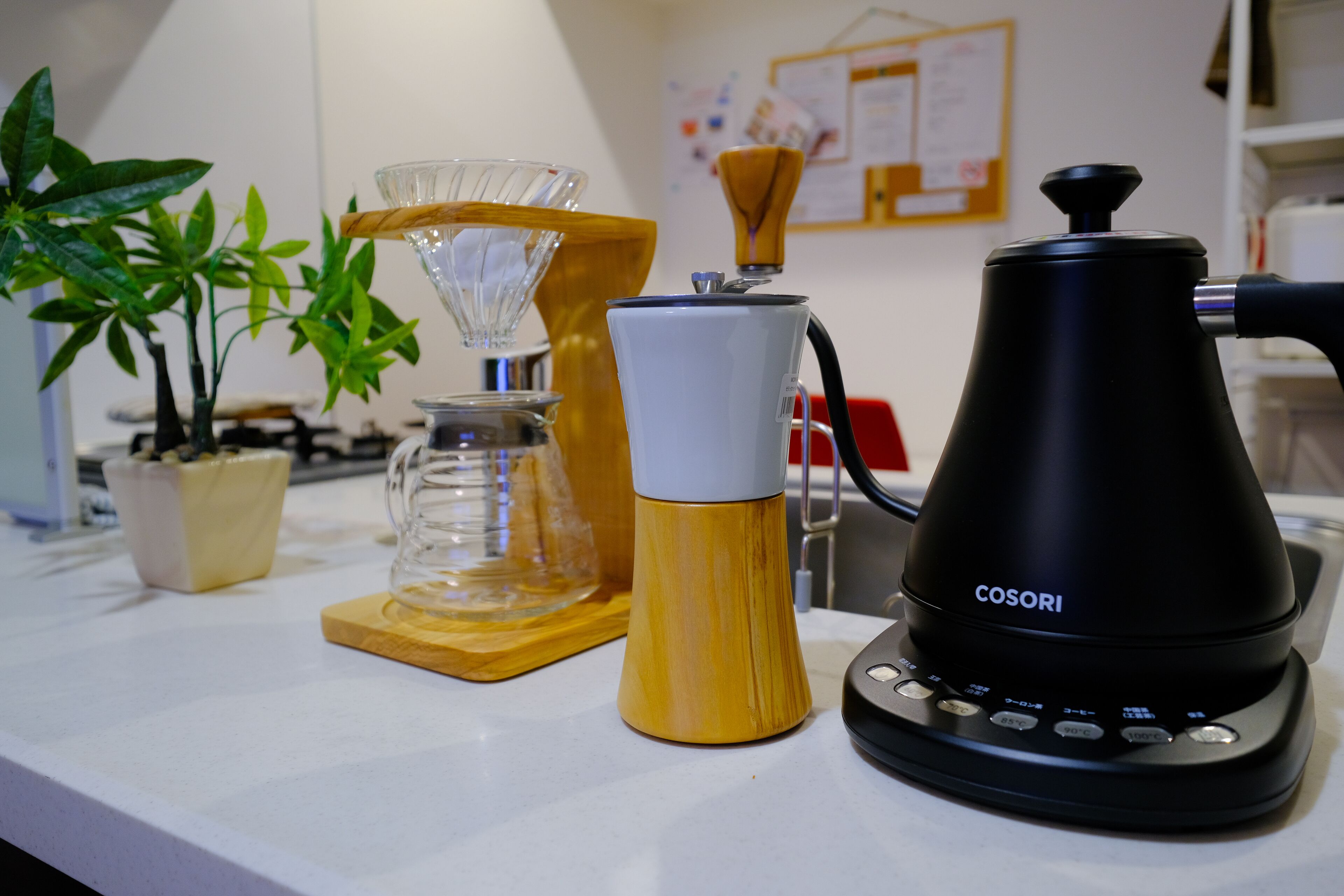 Una encimera de cocina con una cafetera, una jarra de vidrio y una jarra de madera.
