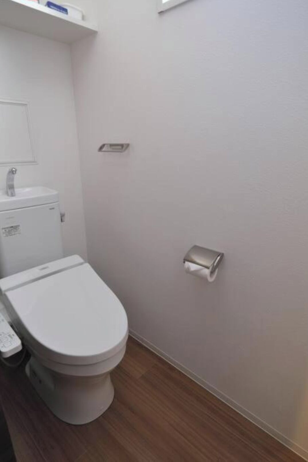 A bathroom with a toilet, a sink, and a toilet paper holder on the wall.