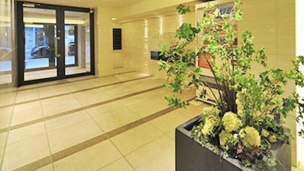 A spacious lobby with a large planter of flowers, a reception area, and a view of the street outside. - Kicon-hotels Marunouchi (Nagoya)