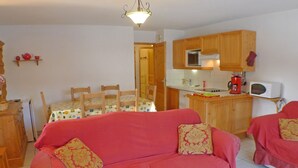 A cozy living room with a red sofa, wooden cabinets, and a tiled floor. - Charming Apartment in Samoëns with Balcony and Parking, Sleeps 6 (Samoëns)