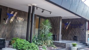 A modern building entrance with a prominent 'TURKAY' sign, a glass door, and a small garden area with plants. - Turkay Hotel (Konyaalti)