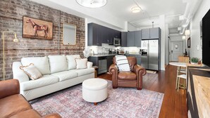 A modern living room with a white sofa, a brown leather armchair, and a patterned rug.