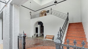 A spacious interior with a brick floor, white walls, a wooden bench, and a staircase with ornate metal railings. - Eagle Exec Loft In Downtown Statesboro (Statesboro)