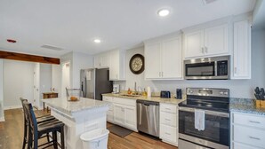 A modern kitchen with white cabinetry, stainless steel appliances, and a central island. - Eagle Exec Loft In Downtown Statesboro (Statesboro)