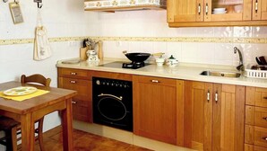 Une cuisine avec des meubles de rangement en bois, une cuisinière, un évier et une table à manger.