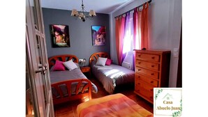 Une chambre avec deux lits, une commode et deux tableaux accrochés au mur.