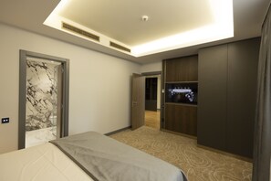 A modern hotel room with a bed, a wardrobe, a vanity with a mirror, and a ceiling light.