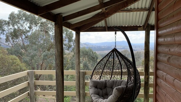 A wooden deck with a hanging chair and a view of the landscape. - Mansfield Colonial Cabin with Stunning Views (Mansfield)