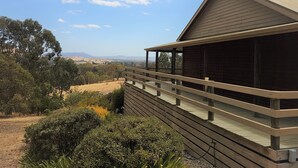 A wooden building with a balcony overlooking a landscape with trees and distant hills. - Mansfield Colonial Cabin with Stunning Views (Mansfield)