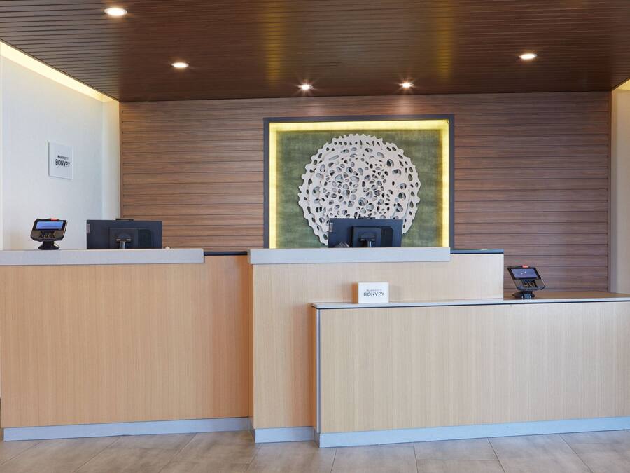 A reception desk with two counters, a digital kiosk, and a framed artwork on the wall.