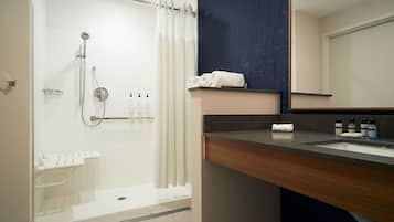 Un baño moderno con cabina de ducha de vidrio, tocador de madera con lavamanos y un espejo grande.