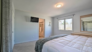 Un dormitorio con cama, ventana, puerta y una lámpara en el techo.