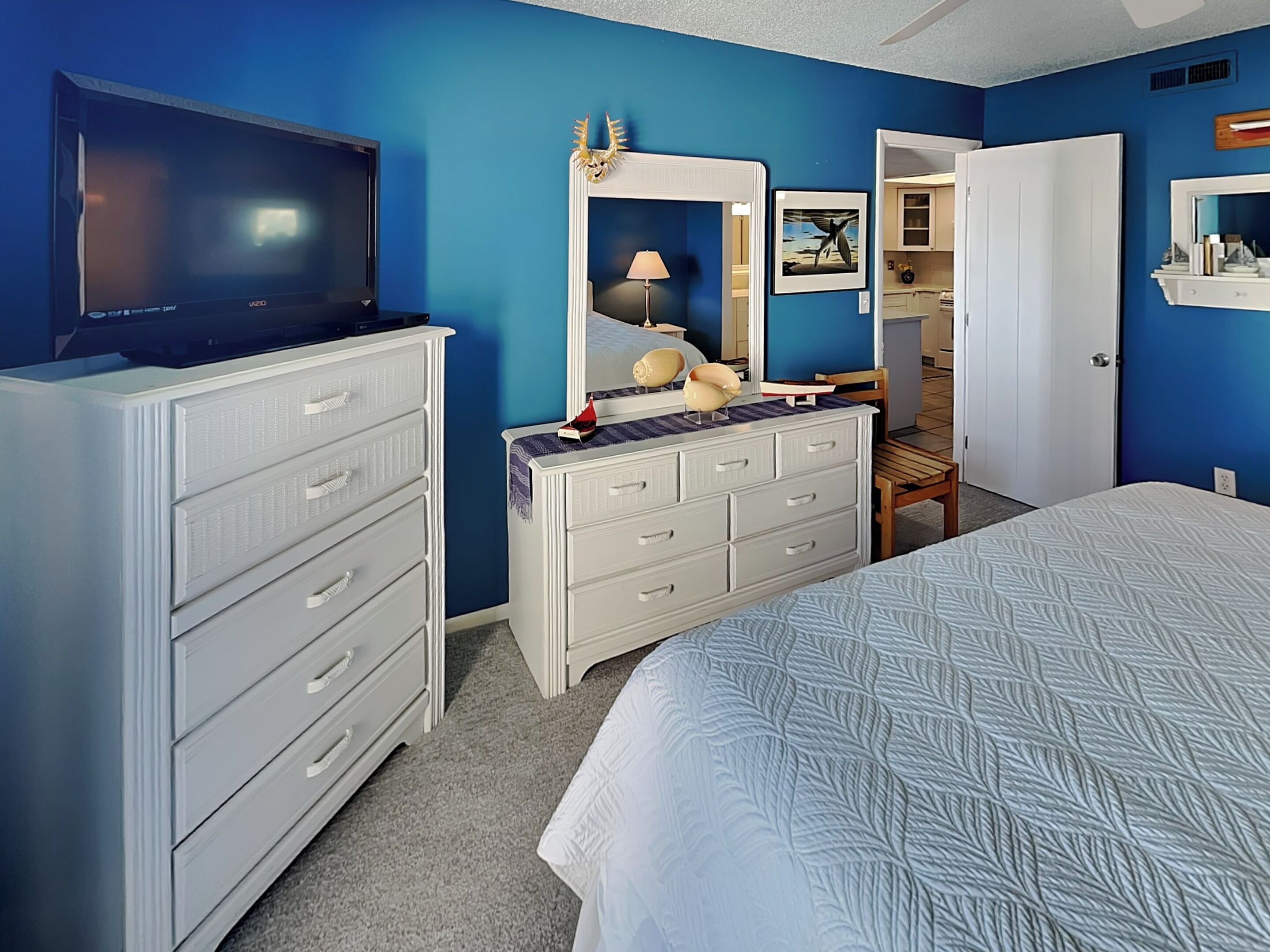 Un dormitorio con cama, cómoda, televisor y espejo.
