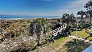 A coastal view with a wooden staircase leading to a grassy area, palm trees, and a beach in the background. - Quail Hollow by Distinctive Beach Rentals (St. Augustine)