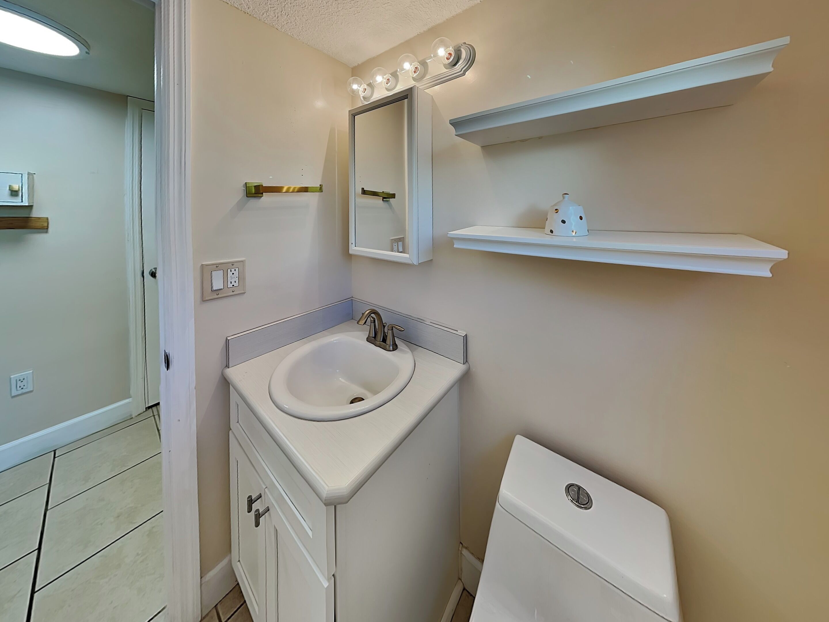 A bathroom with a sink, mirror, vanity, and toilet.