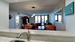 A modern kitchen with a marble countertop, stainless steel sink, and pendant lighting. - Barefoot Trace by Distinctive Beach Rentals (St. Augustine)
